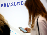 The Samsung logo is pictured as a woman checks the phone during the annual Web Summit technology conference in Lisbon, Portugal on November...