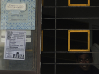 A man smiles from inside a window which has an anti-sexism message written on a Sanitary napkin on the outer sideduring a Sanitary napkin pr...