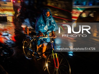 A man using plastic to cover his body while riding a bicycle at Dhaka, Bangladesh, 4 April, 2015. (