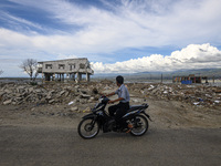 Drivers pass in front of a house damaged by the tsunami in Kampung Lere Beach, Palu Bay, Central Sulawesi, Indonesia on January 9, 2020. The...