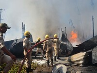 Fire Fighter spray water to extinguish a fire which broke out at Burma Camp in Dimapur, India north eastern state of Nagaland which have bur...