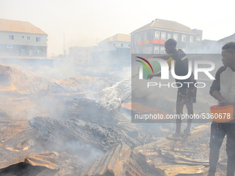 Two men with bowl of water trying to put out a fire that broke out at the popular timber market in Mushin, Lagos January 25, 2020. There hav...