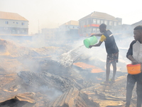 Two men with bowl of water trying to put out a fire that broke out at the popular timber market in Mushin, Lagos January 25, 2020. There hav...