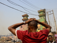 A man makes a gesture at the scene of fire that broke out at the popular amu timber market, Lagos, January 25, 2020. There have been no casu...