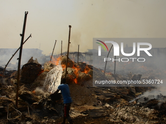 A man with a bowl of water trying to put out a fire that broke out at the popular timber market in Mushin, Lagos January 25, 2020. There hav...