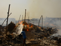 A man with a bowl of water trying to put out a fire that broke out at the popular timber market in Mushin, Lagos January 25, 2020. There hav...