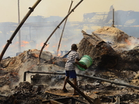 A boy with a bowl of water trying to put out a fire that broke out at the popular timber market in Mushin, Lagos January 25, 2020. There hav...