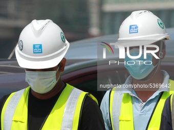 Indian and Sri Lankan construction workers walk out of a mega-construction site wearing  face masks following  the  Corona virus outbreak in...