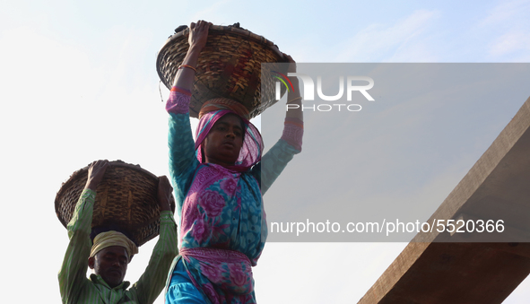 Bangladeshi laborers unload coal from boats  ahead of International Women's Day at the River Turag in Dhaka, Bangladesh, on March 7, 2020. 