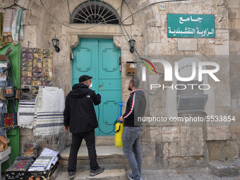 Two men spray a building entrances along the Via Dolorosa Street, a processional route in the Old City of Jerusalem, believed to be the path...