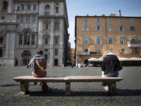 Two people sit one meter away from each other on a bench in Navona Square during the Coronavirus emergency, on March 10, 2020, in Rome, Ital...