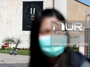 A woman wearing a mask walks by the University of Lisbon, which suspended all teaching activities as part of precautionary measures against...