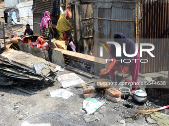 A Bangladeshi Slum-dweller busy with cooking food inside a slum after a devastating fire that broke out at Rupnagar slum on March 11, in Dha...