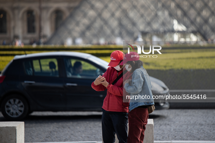 A tourist couple wearing face mask near the pyramide of the Louvre museum in Paris, France, on March 13, 2020. The day after the President '...