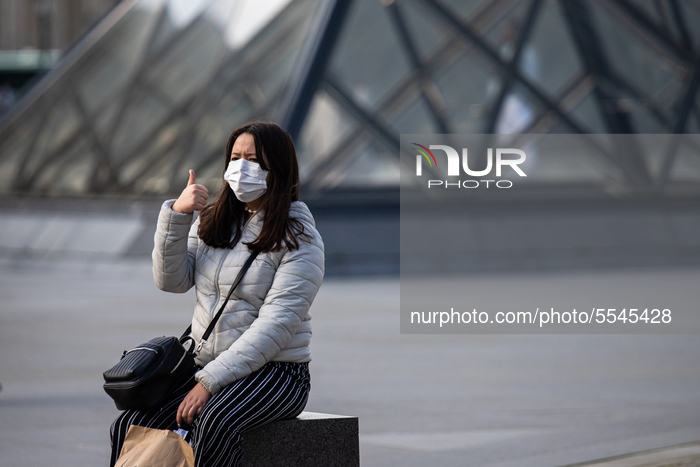 A tourist  wearing face mask near the pyramide of the Louvre museum in Paris, France, on March 13, 2020. the day after the President 's inte...