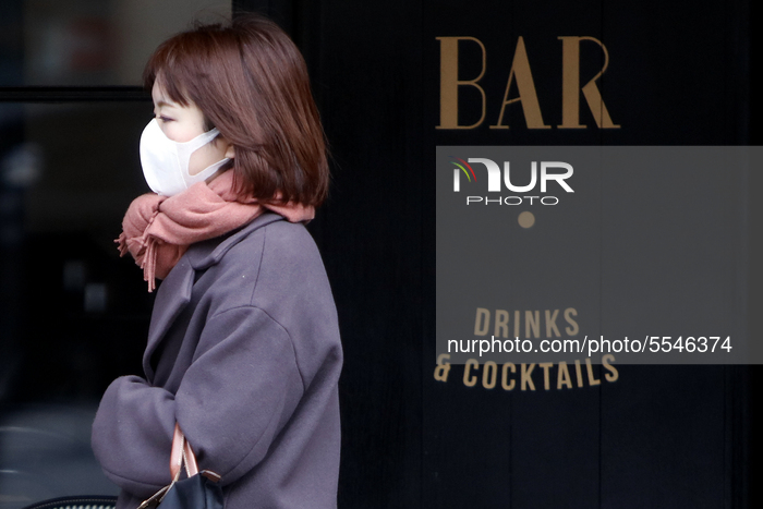 Woman wearing a protective mask walks a front a bar in Saint Germain headquarters in Paris, France on March 14, 2020. RATP and SNCF has anno...