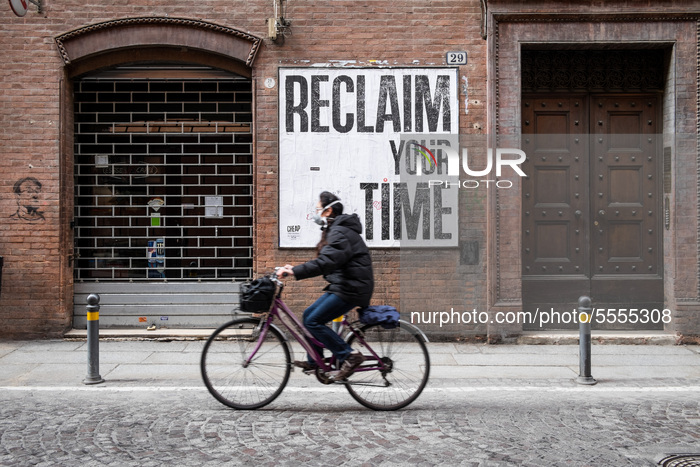 A man on a bicycle wearing a mask on March 13th 2020 in Bologna (Italy) passes in front of a poster that reads: 'Reclaim your time'.
In Mar...