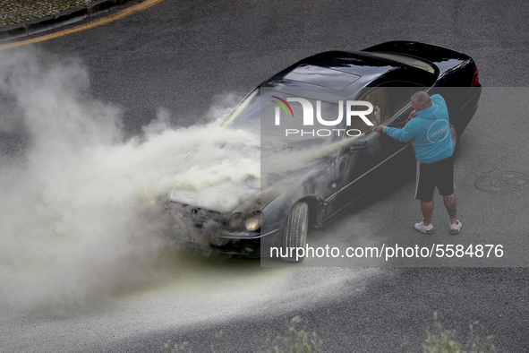 A man tries to extinguish a fire in his car in Cascais, Portugal, on March 26, 2020. 