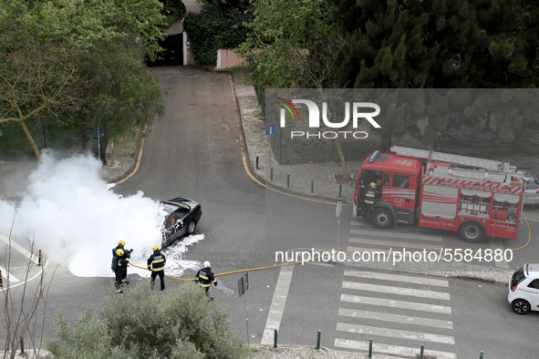 Firefighters try to extinguish a fire in a car in Cascais, Portugal, on March 26, 2020. 