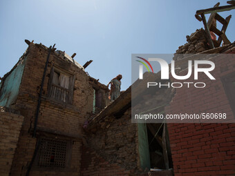 A woman walk in the roof of her damaged house as she's gonna removed rubbles caused by the earthquake in the small village of Sankhu outside...