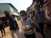 A boy wearing a face mask holds a list as he walks along a street in Mumbai, India on April 11, 2020. India continues in nationwide lockdown...