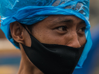 A man wearing a protective face mask covers his head with a plastic in a slum area in Tondo, Manila in the Philippines on April 18, 2020. Ab...