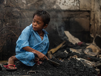 A boy collects fire debris to be sold in junk shops after a fire  broke out in a slum area in Tondo, Manila in the Philippines on April 18,...