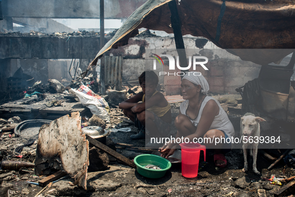 A woman prepares lunch outside the debris of her house destroyed by the fire that broke out in a slum area in Tondo, Manila in the Philippin...