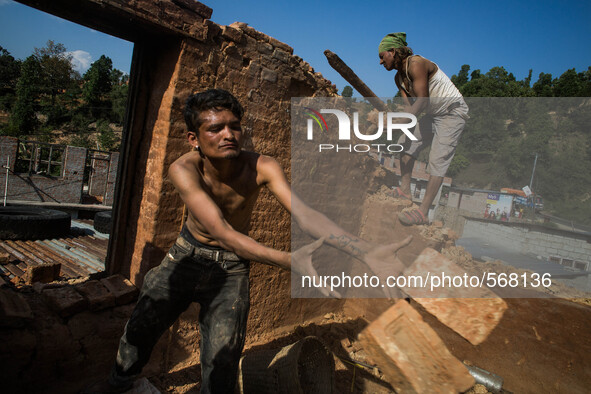 Ramesh (left) and Sunil (right) are breaking down their destroyed house due to earthquake. Dhading, Nepal. May 5, 2015. 