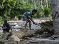 A child collects wood from his house that was lost in a flash flood in Poi Village, South Dolo Subdistrict, Sigi Regency, Central Sulawesi P...