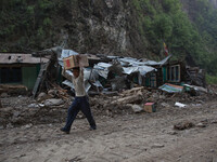 A boy pass through a collapsed abandoned village as he's carrying goods found in a destroyed Chinese truck at 30 minutes walk from here on t...