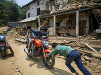 Kids are playing on the motor bike in front of their destroyed house. Sindhupal Chowk, Nepal. May 7, 2015. (