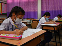 Elementary school students wearing face masks in social distancing as a preventive measure in a class is a demonstration of learning amid th...