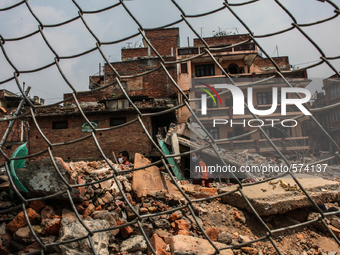 People are passing in front of a broken house at Swambhu, Kathmandu, Nepal, 8 May 2015. (