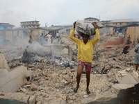  A girl walk through some rubble carrying some remains of her properties as fire razed a market called Olaleye Market in the area somolu are...