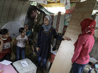 A girl reads out a text as Palestinian student Fajr Hmaid, 13, teaches her neighbours' children an Arabic language lesson as schools are shu...