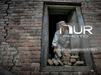 An old man is collecting bricks from his destroyed house. Sankhu, Nepal. May 9, 2015 (