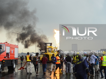 Officials of the Lagos State Management Agency flee the scene while trying to put out the fire, following a gas explosion, involving four ar...