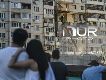 Locals watch Ukrainian rescue workers clean debris after a gas explosion in nine-stored apartment building in Kyiv, Ukraine, 21 June 2020....