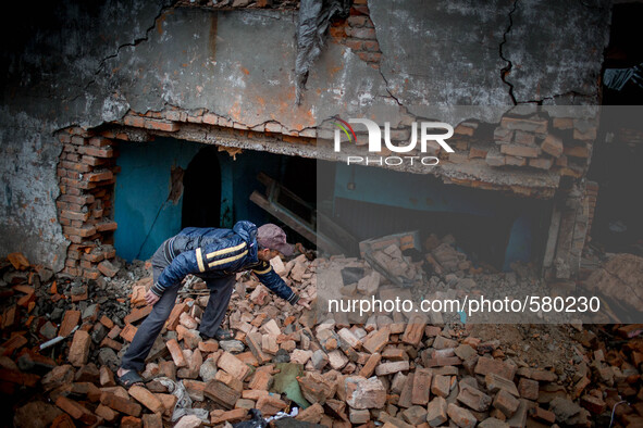 A man is cleaning the rubbles in his destroyed building. Sundhara, Kathmandu, Nepal. May 1, 2015. 