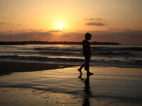 A Palestinian child walks on the Sea of Gaza City beach at sunset on  May 10, 2015 (