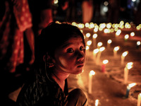 A girl is sitting in front of candle lights to show respect who were the victims of earthquake.  (