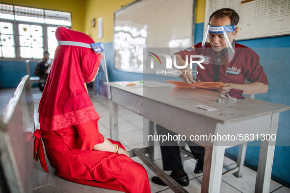 A teacher checking document of a little girl participant for the selection test for entering the school at Depok, West Java, Indonesia, on J...