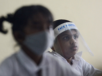 A student wearing a face shield sits in a classroom after their school after 115 days, the school that was shut down during the COVID-19 loc...
