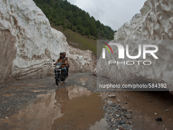 ZOJILA, INDIAN ADMINISTERED KASHMIR, INDIA - MAY 13: A motor cyclist passes passes through the snow-cleared Srinagar-Leh highway on a treach...