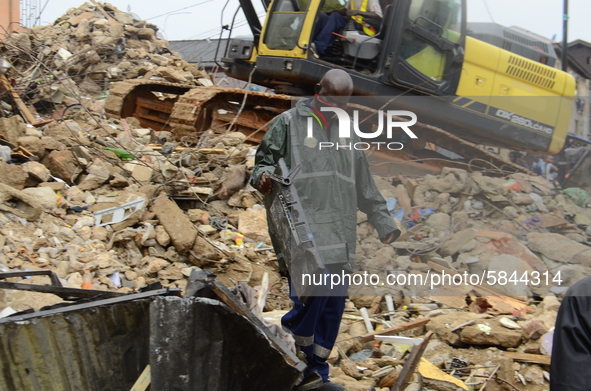 A rescue worker carrying a television among the ruins of a collapsed building, where three persons have been confirmed died and nine injured...
