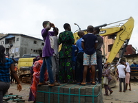 Young boys stand on interlocking stones to help them see remains of the collapsed building, where three persons have been confirmed died and...