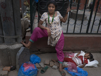 KHATMANDU, NEPAL-- May 14, 2015- In Kathmandu's old city, a vegetable seller with a sleeping infant nearby. The city of Kathmandu is slowly...