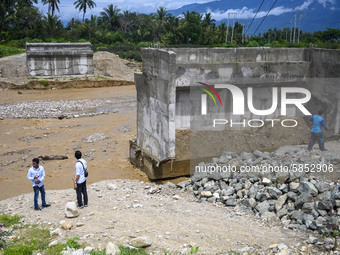 Officers inspect the condition of the Pombewe bridge which was eroded by river water due to flooding in Pombewe Village, Sigi Regency, about...