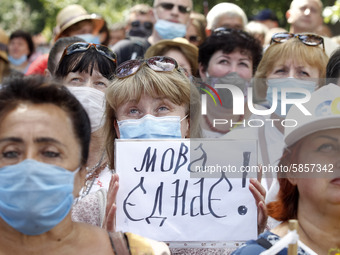 A woman holds a poster reading like 'The language unites!' during a rally in support Ukrainian language and against a bill which offers to e...